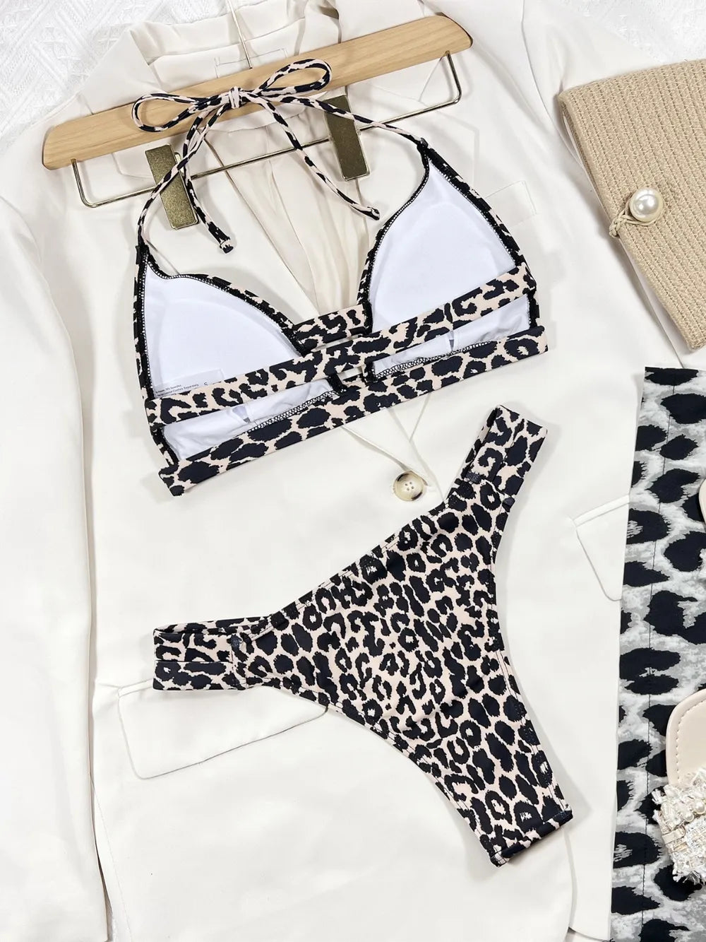 Leopard print bikini set with a white top on a hanger, placed on a light surface.