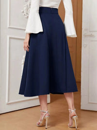 Person wearing a navy blue skirt with a white top in an indoor setting.