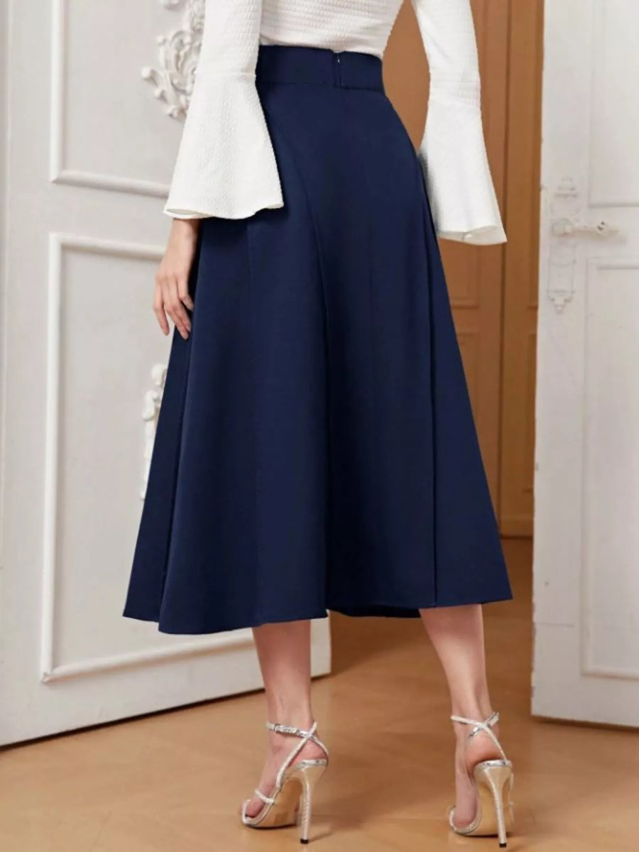 Person wearing a navy blue skirt with a white top in an indoor setting.