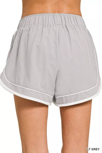 Gray shorts with white trim worn by a person on a white background