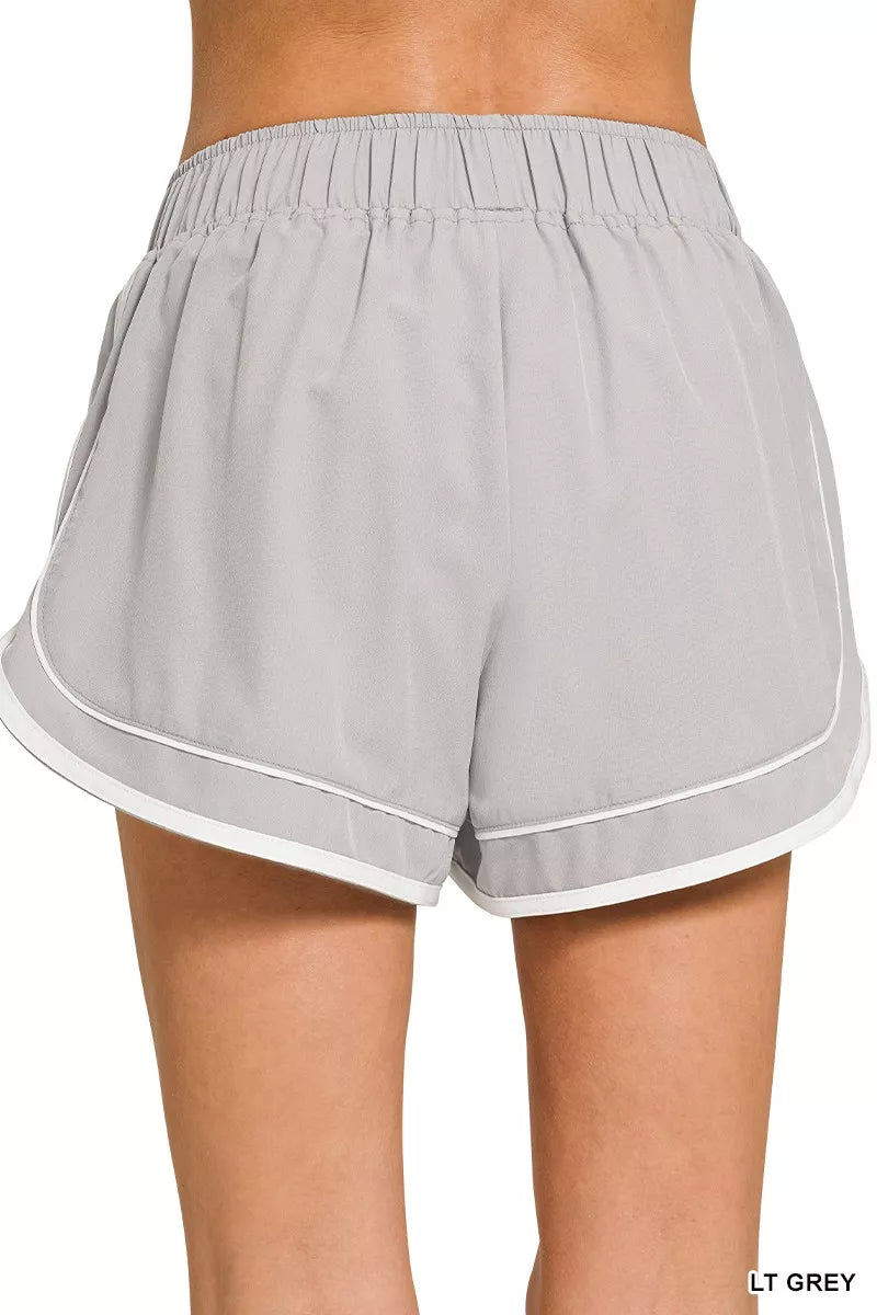 Gray shorts with white trim worn by a person on a white background