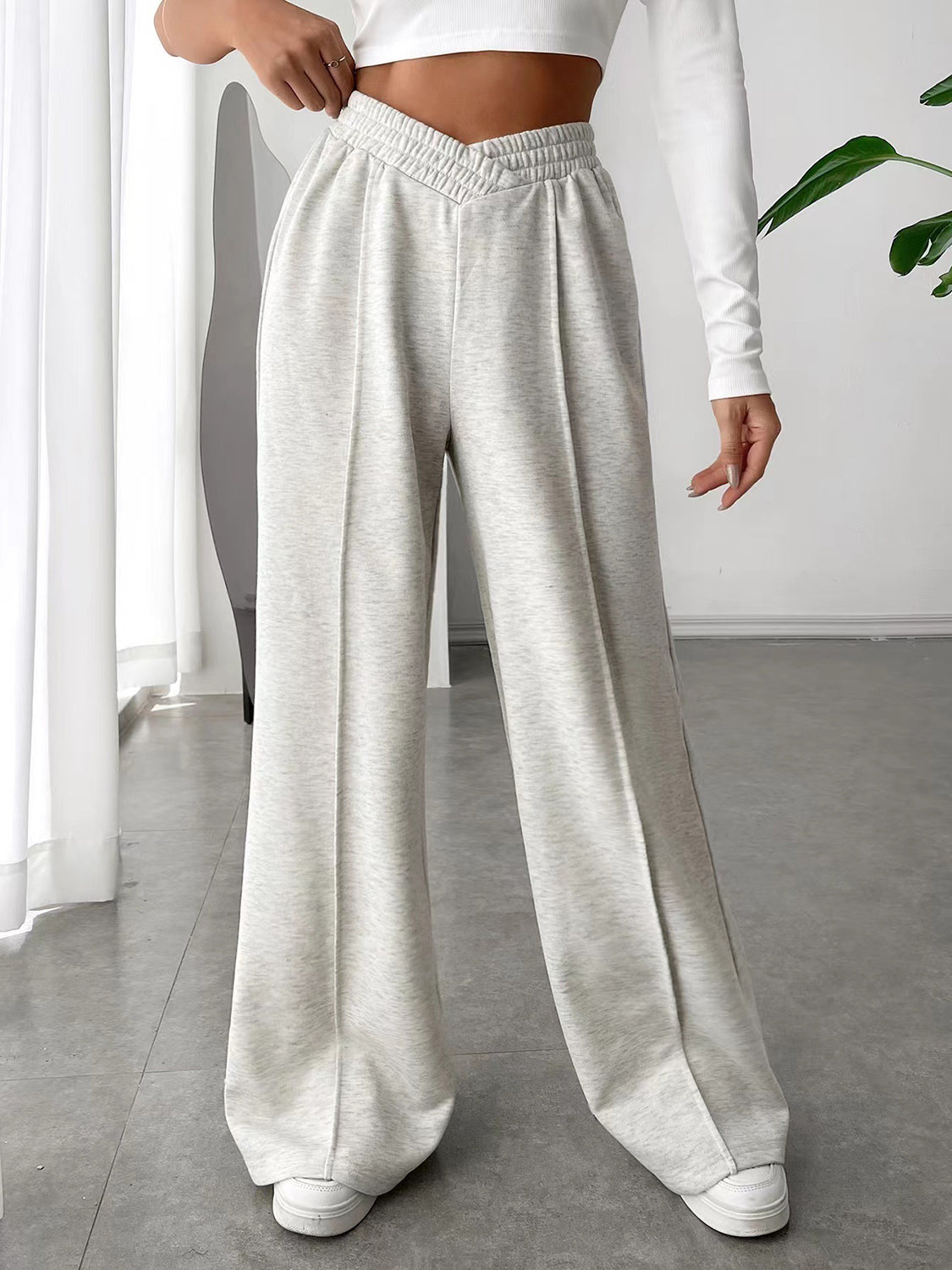 A pair of white elastic waist wide leg pants with pockets, displayed on a model without showing the upper part of the body.