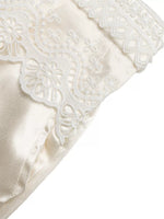 Close-up of a white satin pillow with lace trim on a white background