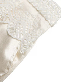 Close-up of a white satin pillow with lace trim on a white background