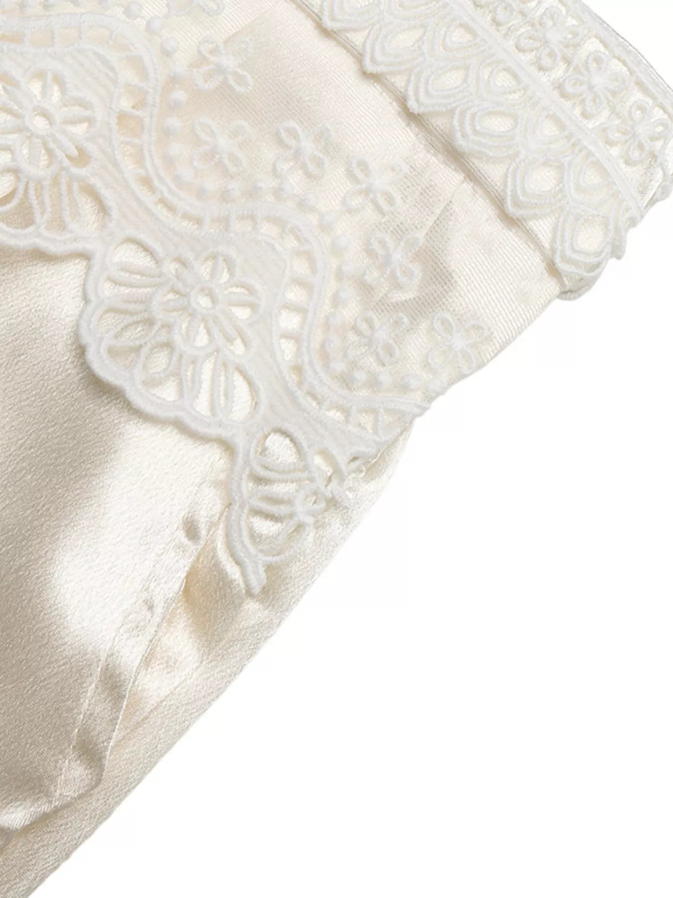 Close-up of a white satin pillow with lace trim on a white background