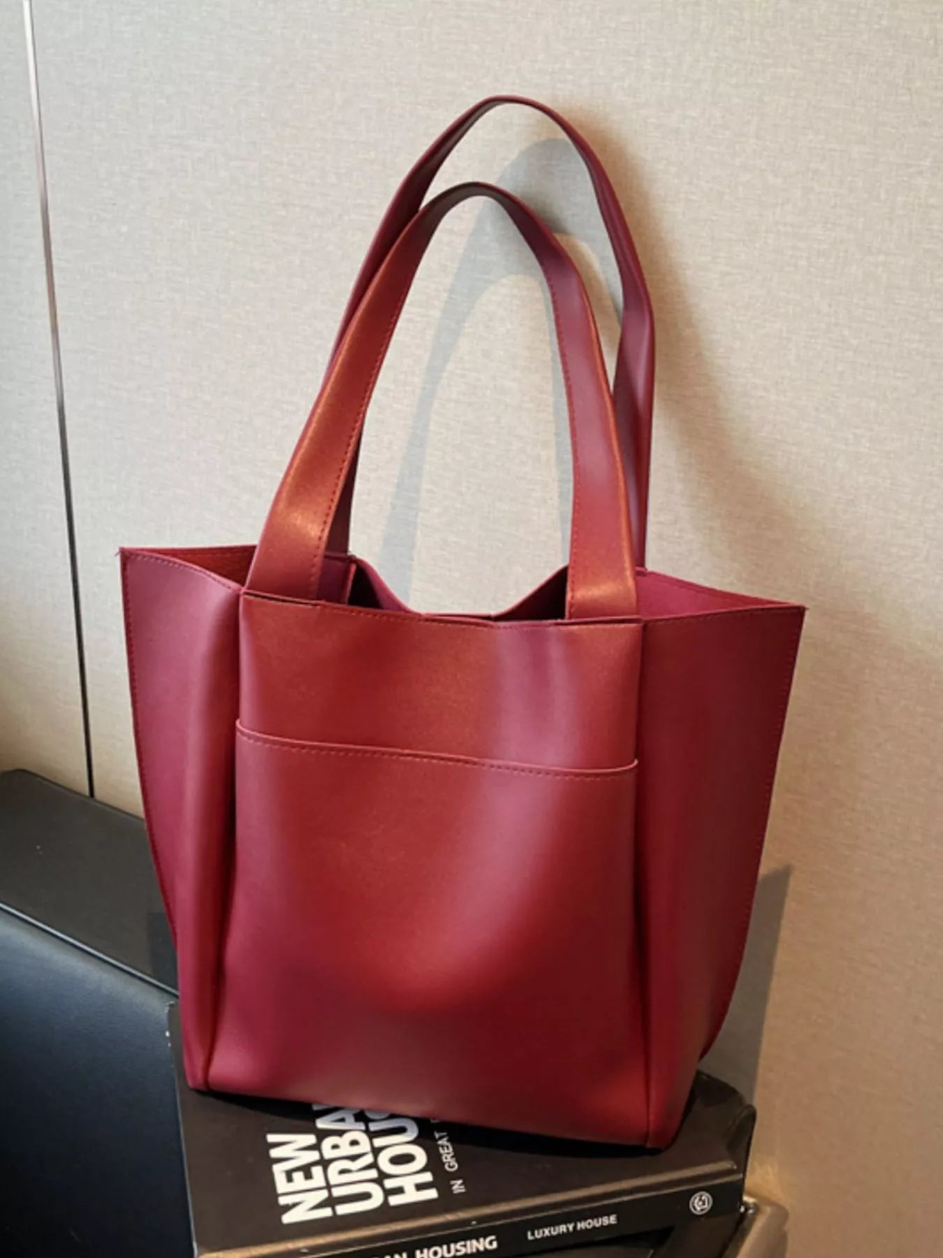 Red tote bag on a stack of books with a neutral background
