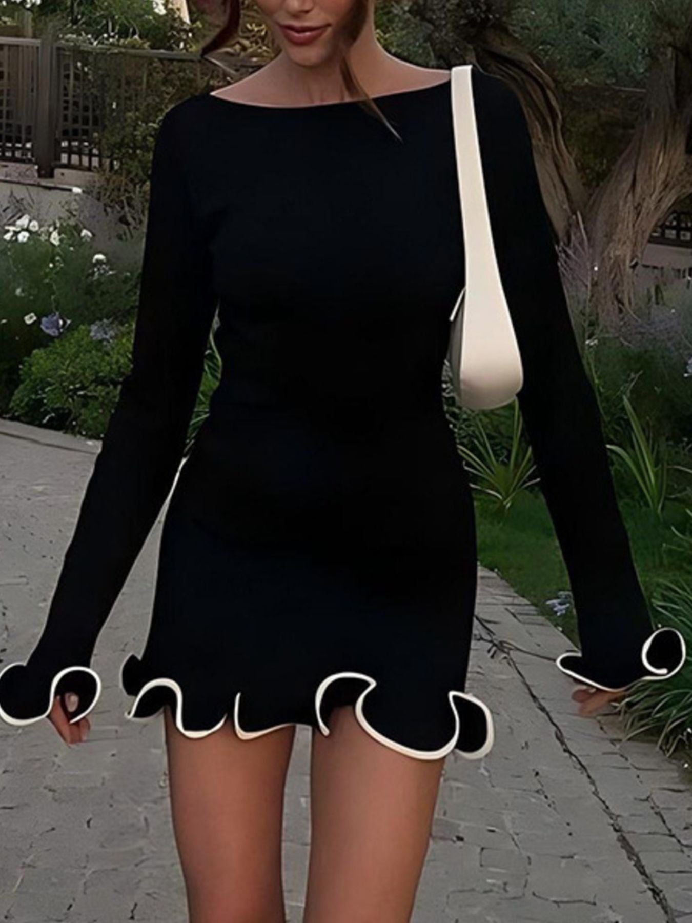 Person wearing a black dress with ruffled hem in an outdoor setting