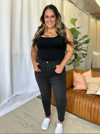 Woman wearing a black top and black jeans standing in a living room.