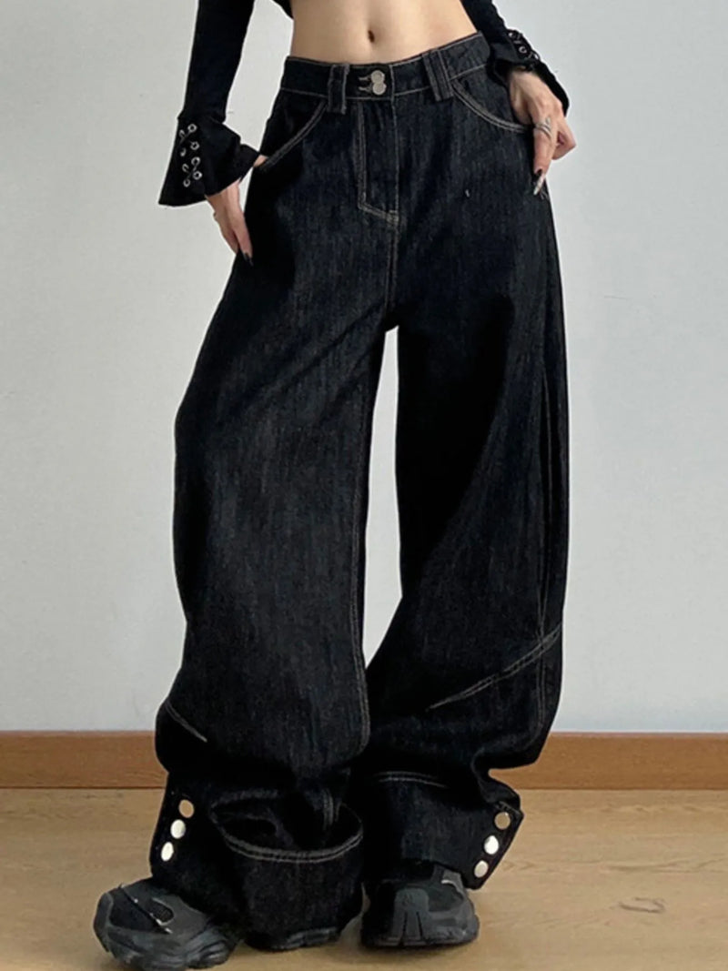 Person wearing wide-leg black jeans with a plain background