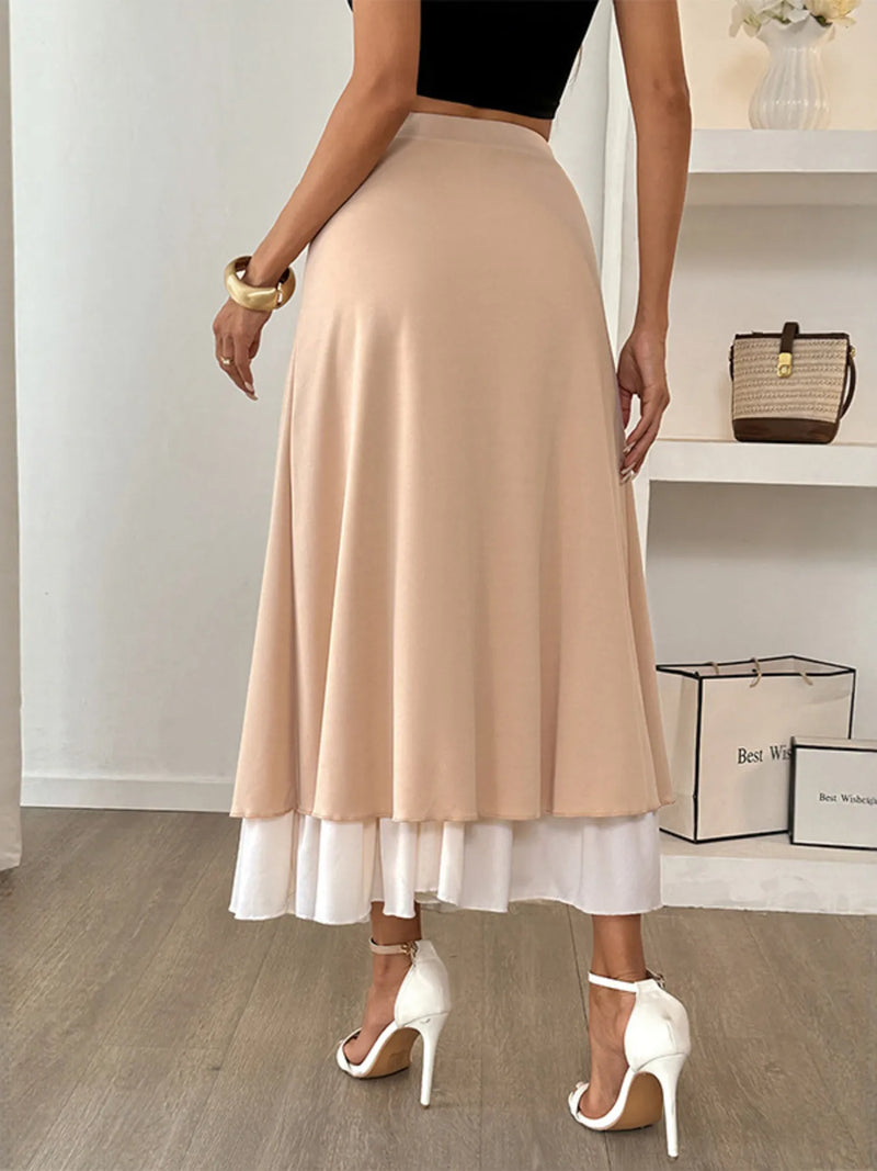 Woman wearing a beige skirt with a white bottom in an indoor setting.