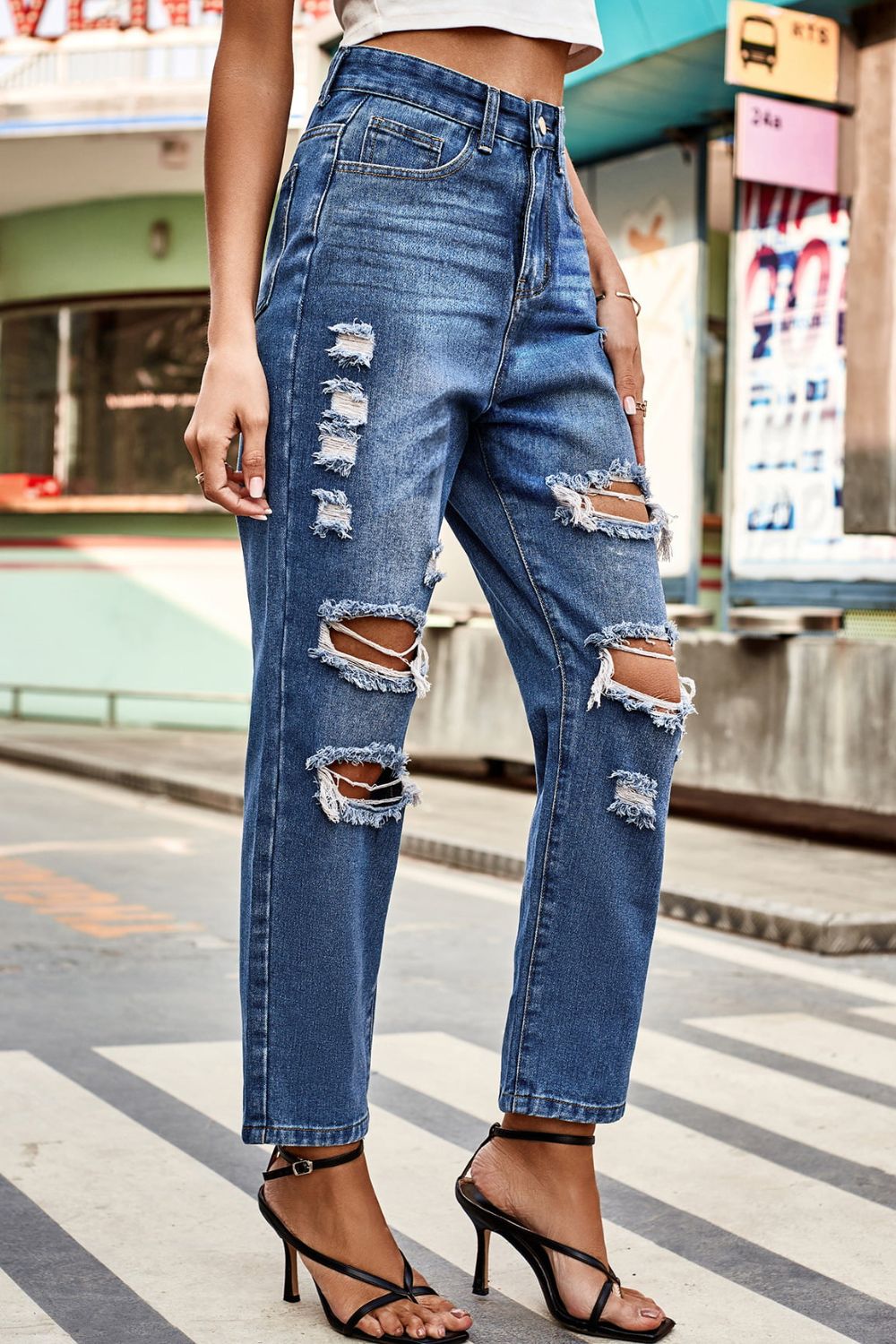Person wearing ripped blue jeans on a city street.