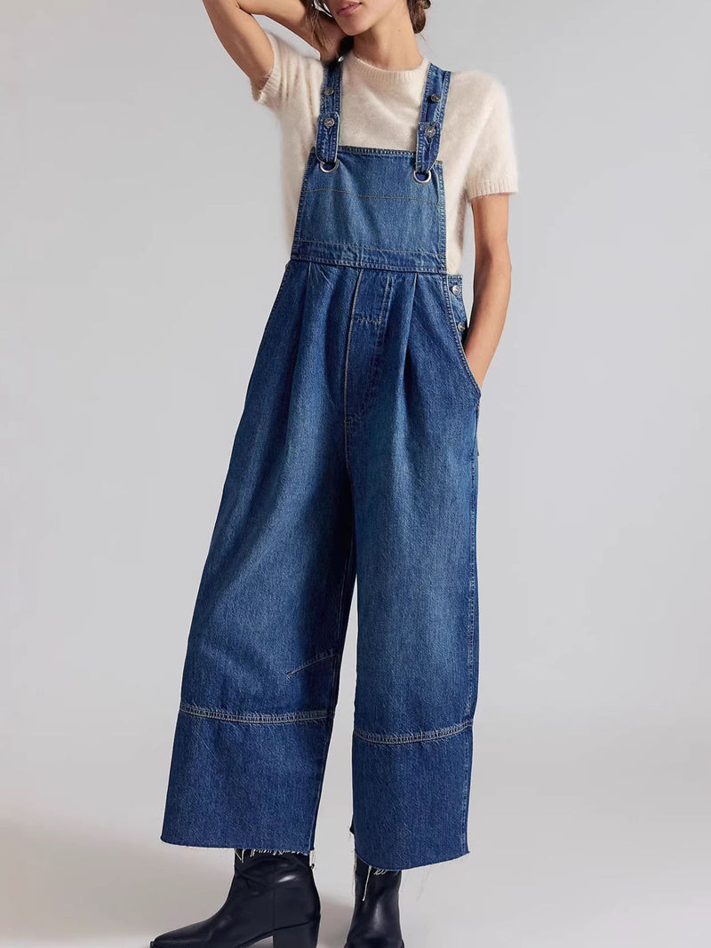 Person wearing blue denim overalls on a plain background