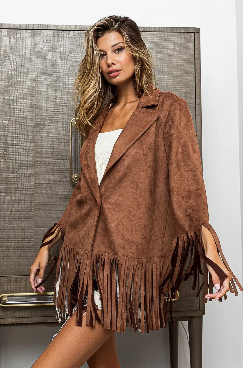 Woman wearing a brown suede fringe jacket indoors.
