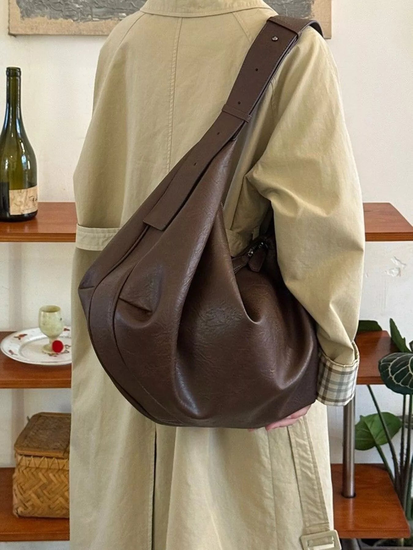 Person wearing a brown leather shoulder bag in an indoor setting