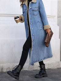 Person wearing a long denim coat with fur trim, holding a coffee cup and clutch.