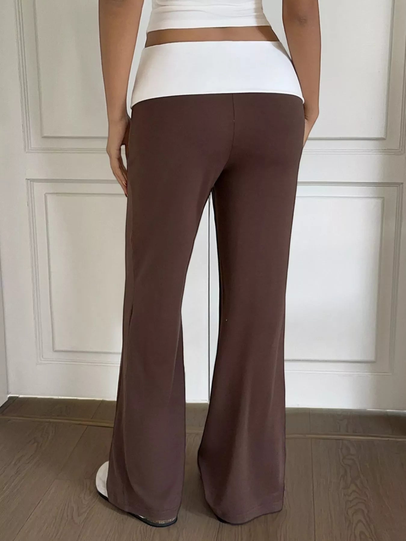 Brown flared pants worn by a person against a neutral background