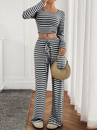 Person wearing a black and white striped outfit with a beige handbag indoors.