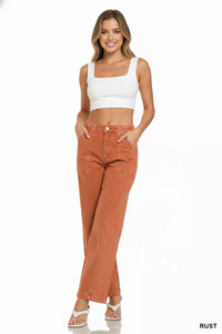 Woman wearing rust-colored jeans and a white top on a white background