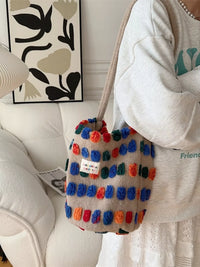 Colorful pom-pom bag held by a person in a home setting