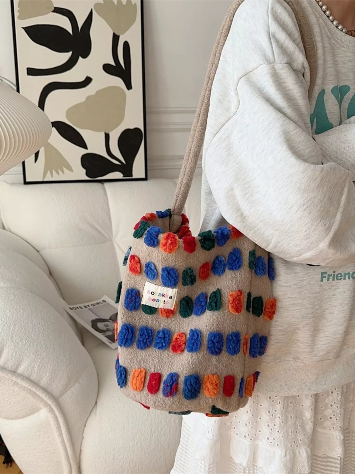 Colorful pom-pom bag held by a person in a home setting