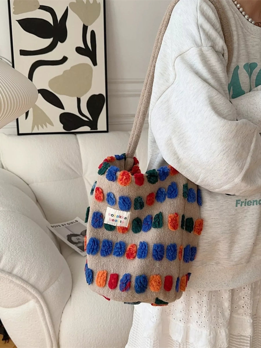 Colorful pom-pom bag held by a person in a home setting