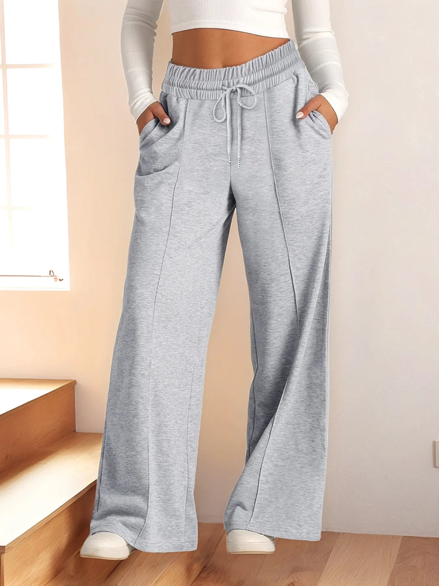 Person wearing gray sweatpants and white top in a minimal indoor setting