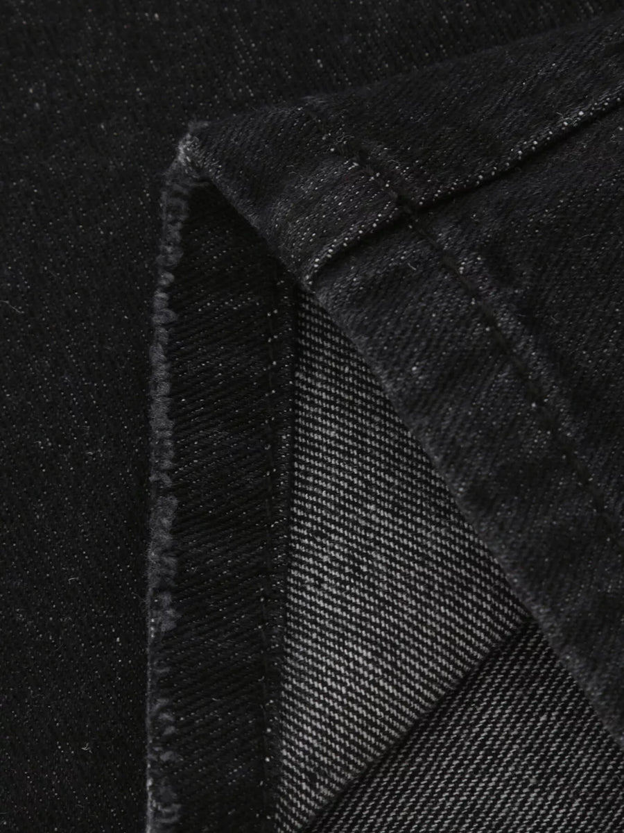 Close-up of black textured fabric with a diagonal pattern on a black background