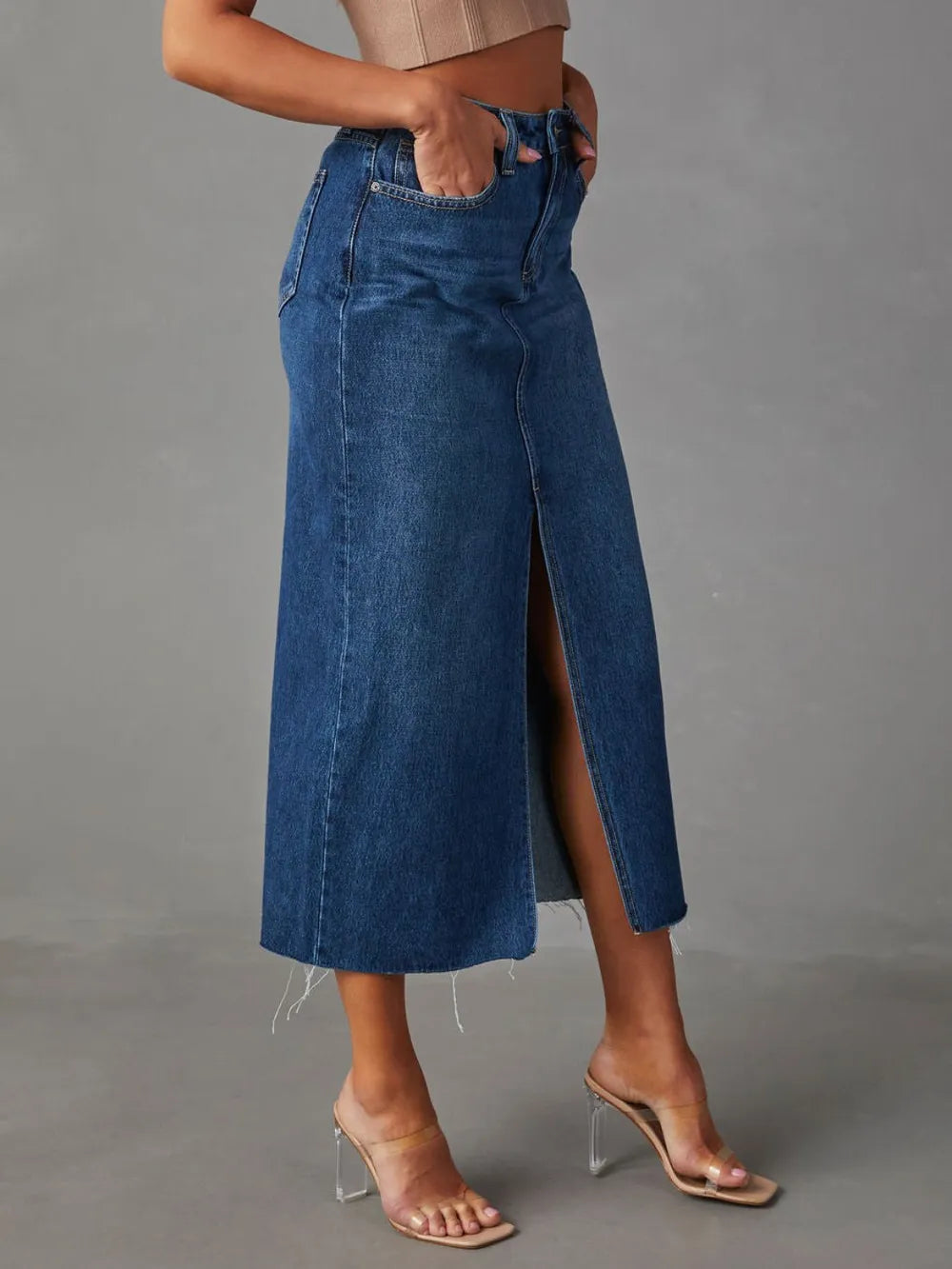 Person wearing a blue denim skirt with a gray background