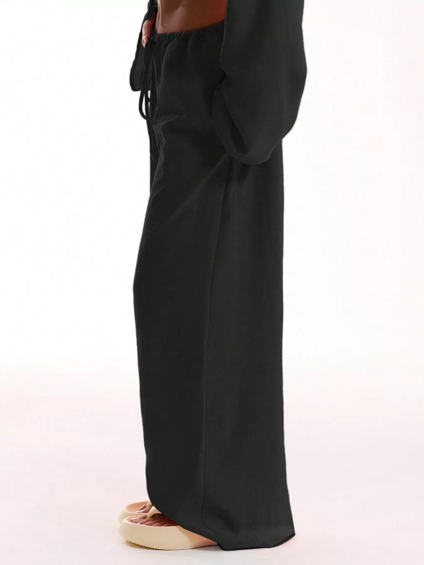 Black wide-leg pants worn by a person on a white background