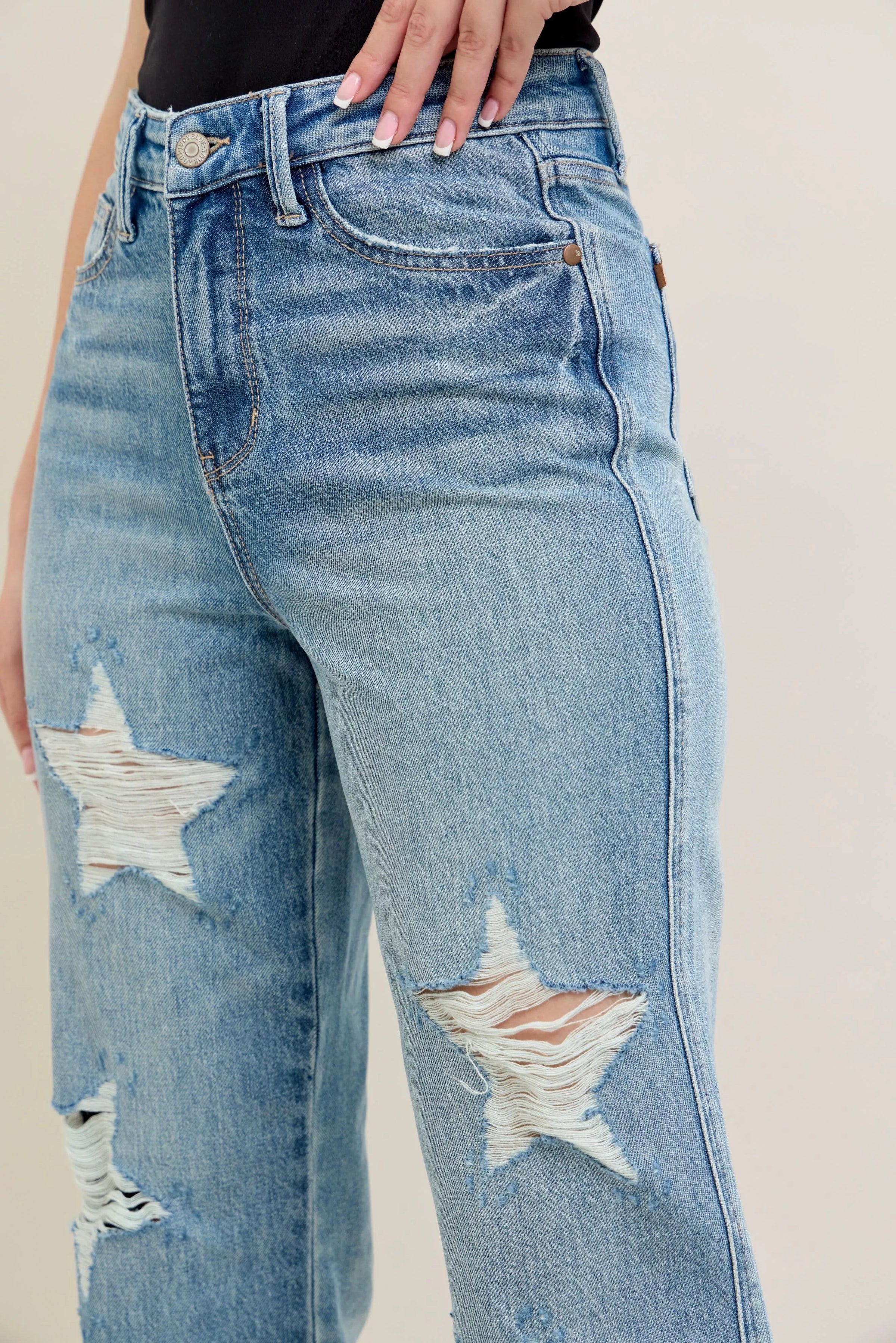 Distressed blue jeans with star designs on a neutral background