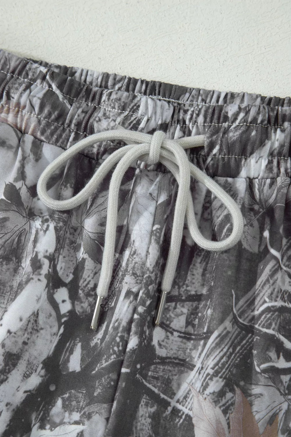 Close-up of a pair of shorts with a floral pattern and drawstring on a light background