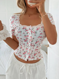 Woman wearing a floral top and white pants in a bedroom setting