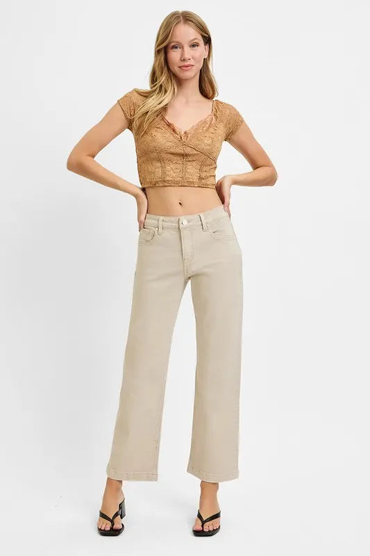 Woman wearing a beige top and light-colored pants on a white background