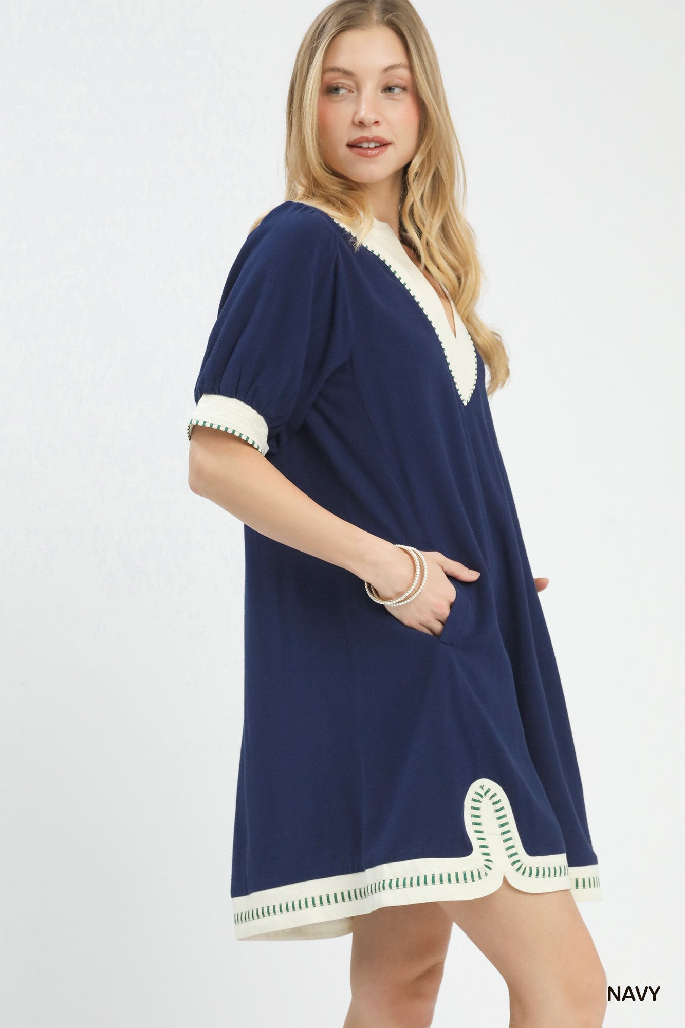 Woman wearing a navy dress with white trim on a light gray background