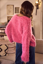 Person wearing a pink fuzzy sweater in a living room setting