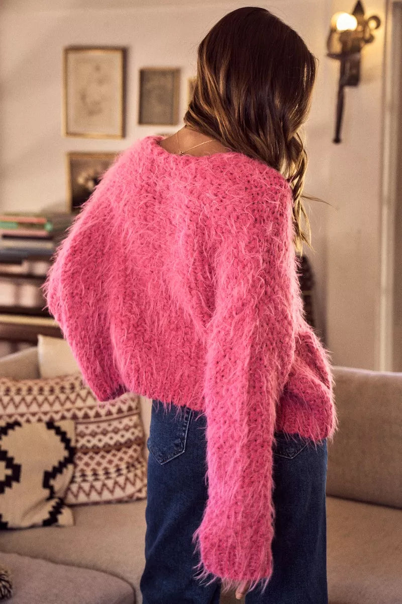 Person wearing a pink fuzzy sweater in a living room setting
