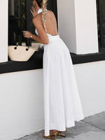 Woman in a white dress standing against a building exterior.