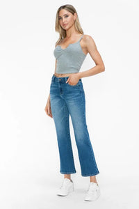 Woman wearing a gray tank top and blue jeans on a white background