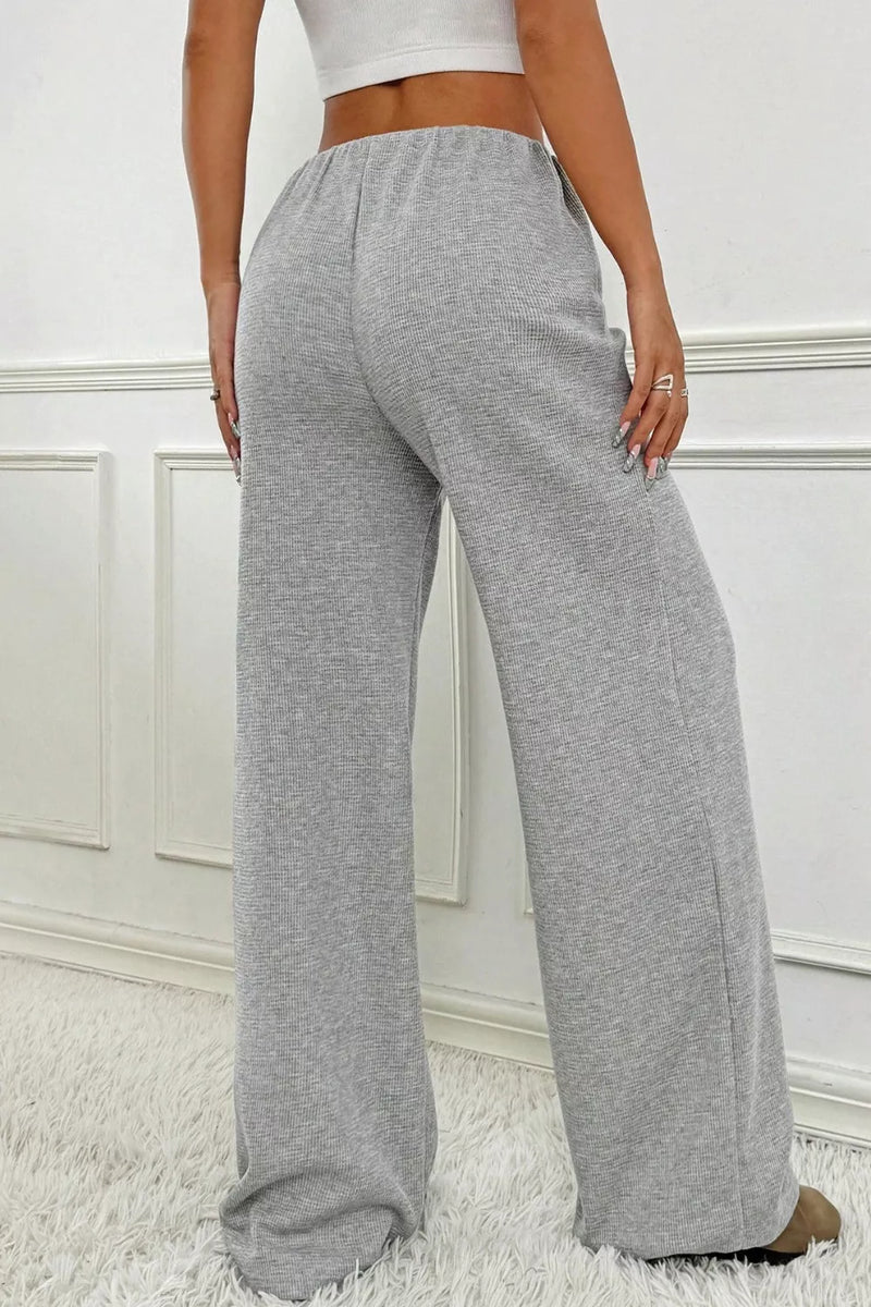 Gray sweatpants worn by a person on a white background