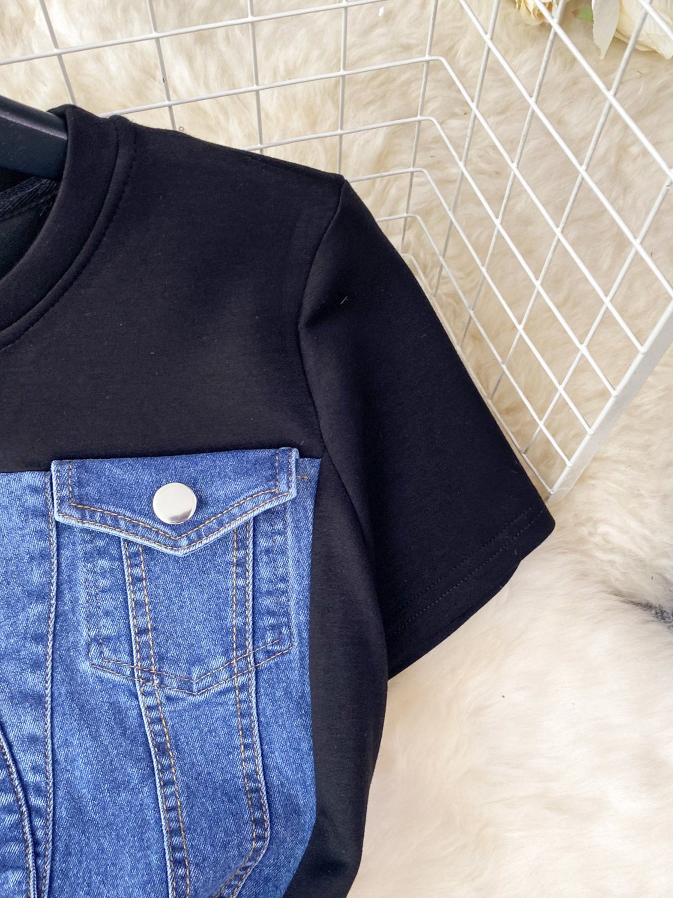 Black t-shirt with blue denim pocket design on a white background