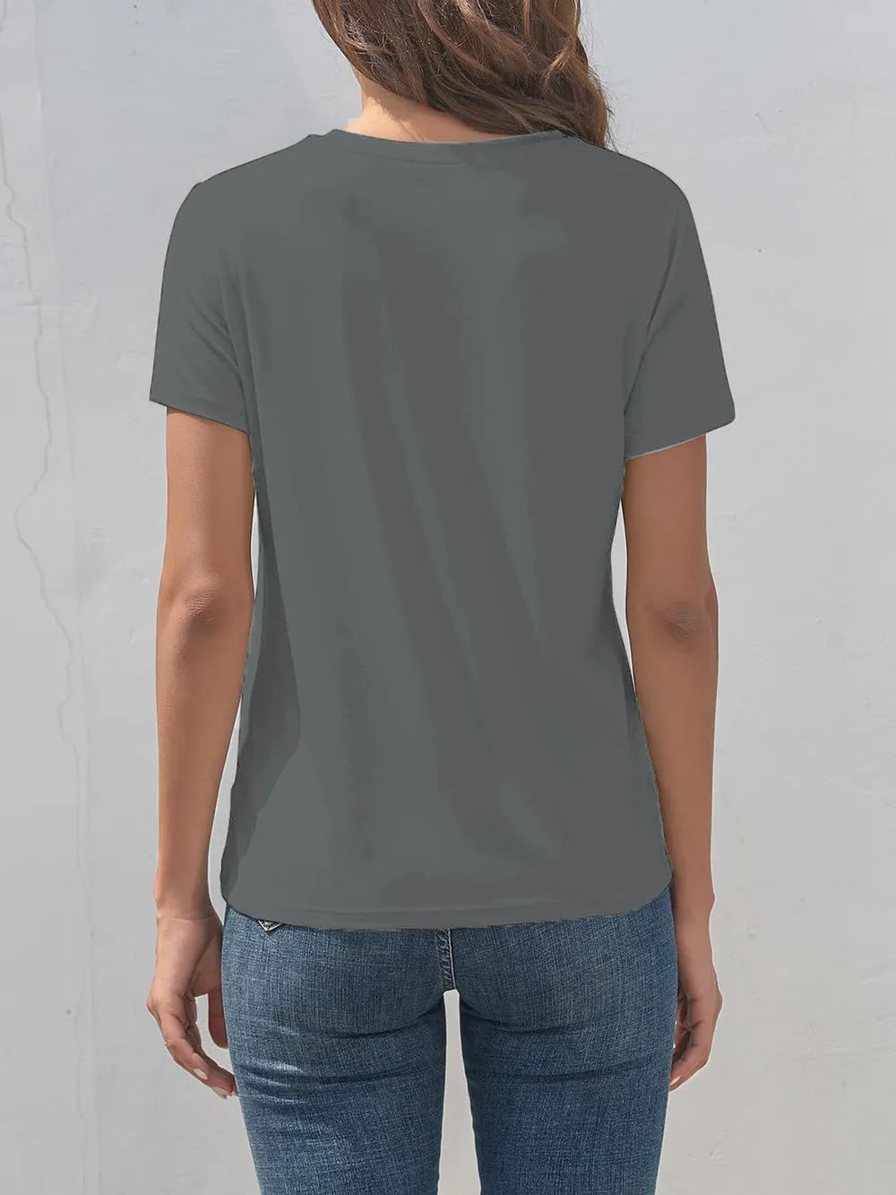 Person wearing a plain gray t-shirt and blue jeans against a light gray background