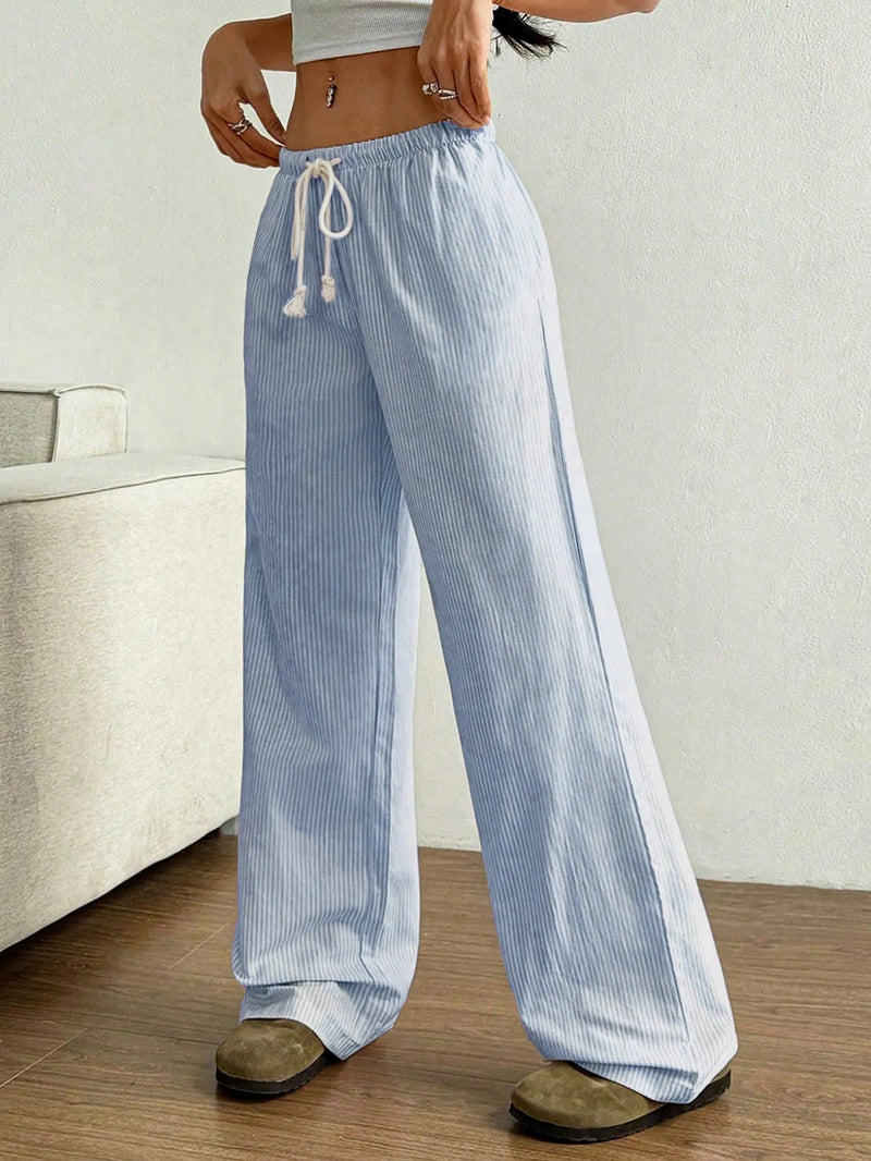 Person wearing light blue and white striped pants in a minimal indoor setting.