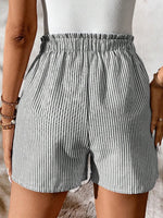 Person wearing gray and white striped shorts on a neutral background
