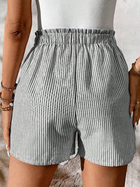 Person wearing gray and white striped shorts on a neutral background