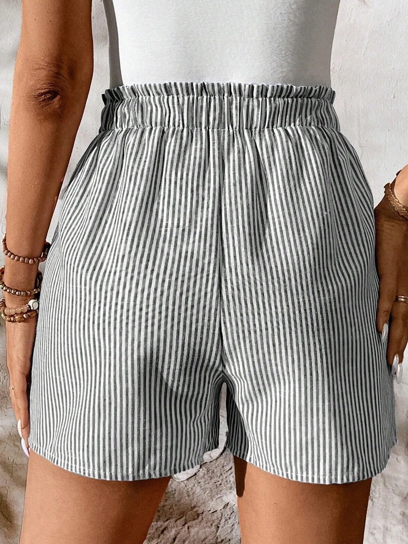 Person wearing gray and white striped shorts on a neutral background