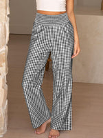 Person wearing black and white checkered pants in a neutral setting