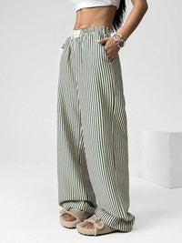 Person wearing green and white striped wide-leg pants on a white background
