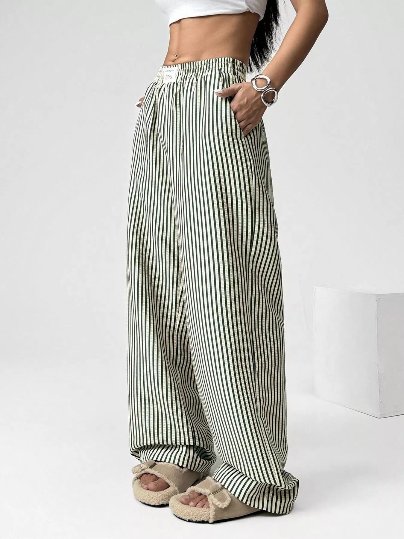 Person wearing green and white striped wide-leg pants on a white background