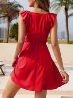 Woman wearing a red dress with ruffled sleeves in an outdoor setting.