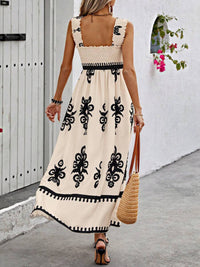 Woman wearing a beige dress with black patterns, walking on a street.